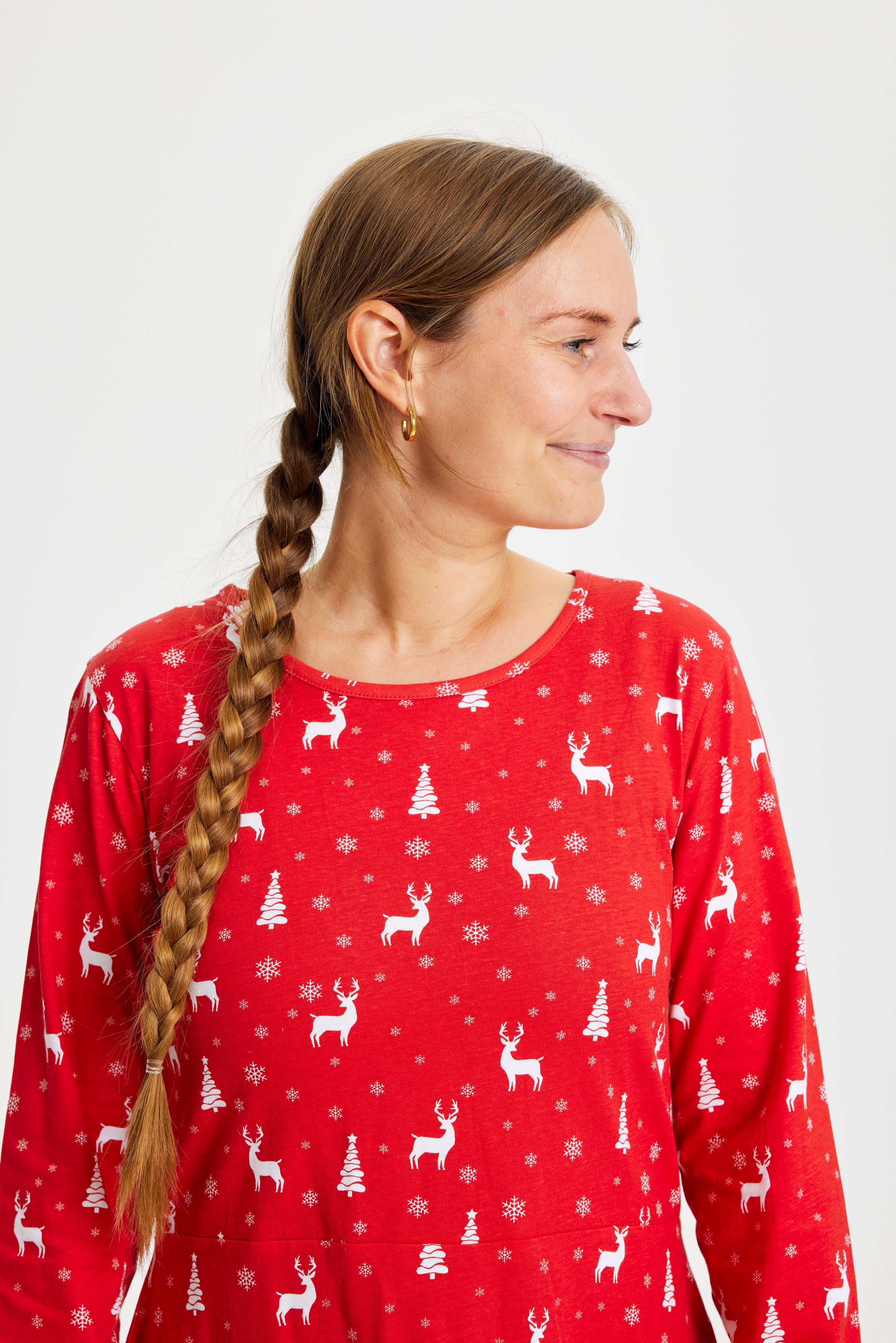 En kvinne ser til siden iført en rød julekjole med reinsdyr på.